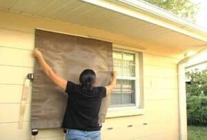 Woman installing a storm catcher easy screen to protect windows
